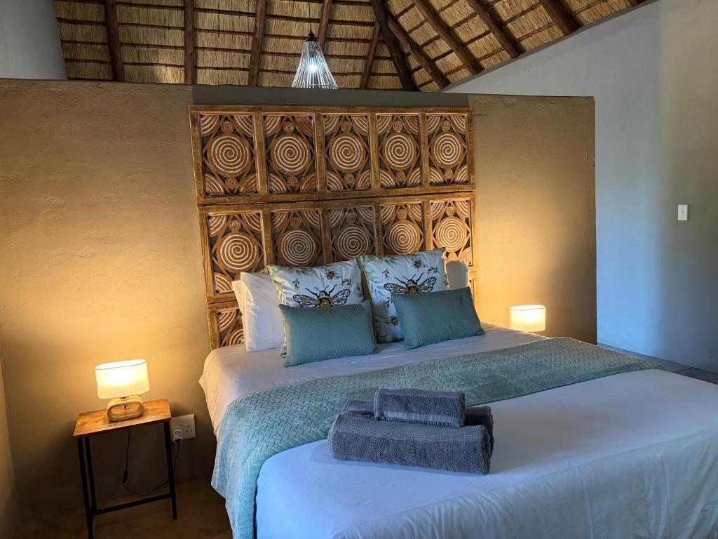 a bedroom with a large bed with a wooden headboard at Shiandi Cottage in Hoedspruit