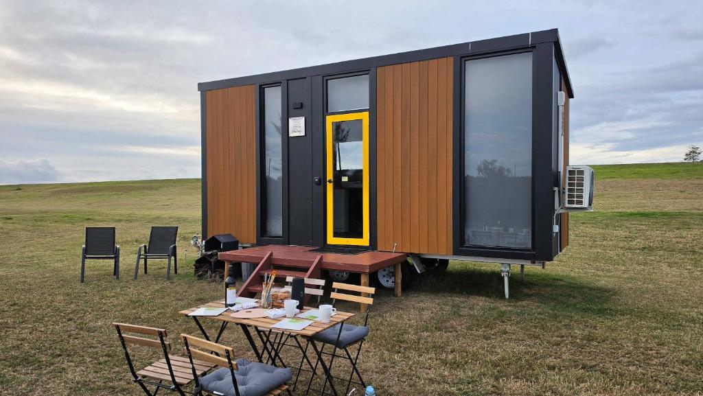 a tiny house with a table and chairs in a field at Oscars Retreat 1 by Tiny Away in Raworth