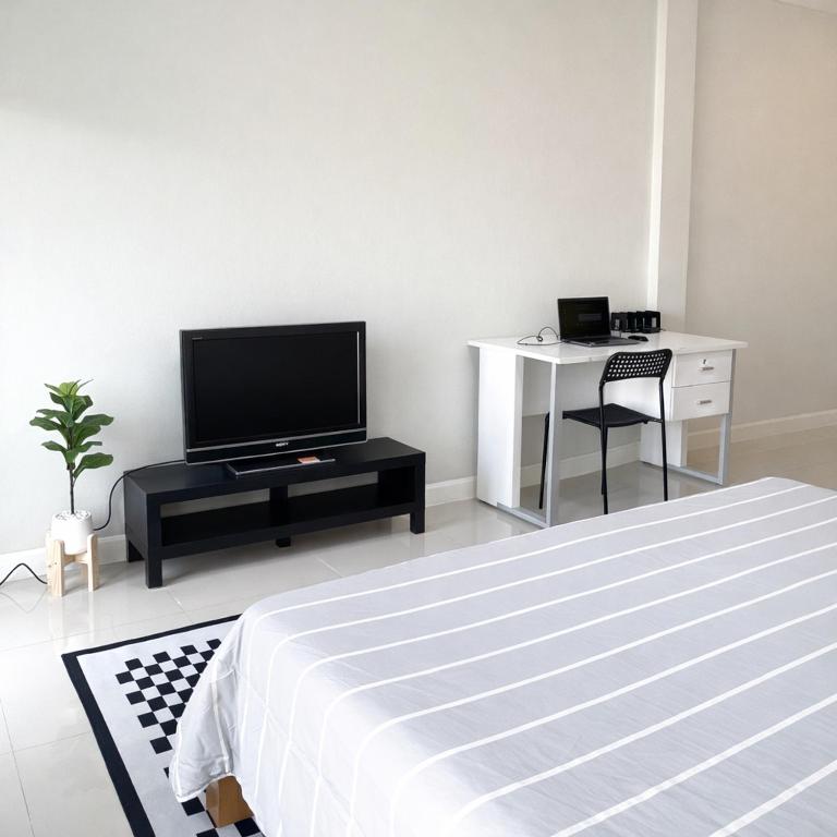 a bedroom with a bed and a tv and a desk at Mayeen cat hotel in Chiang Mai