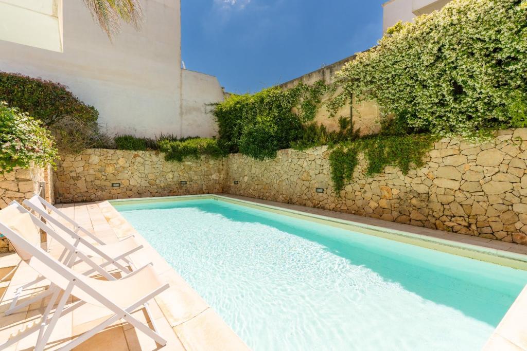 a swimming pool with two chairs and a stone wall at Residence Quattro Colonne in Santa Maria al Bagno