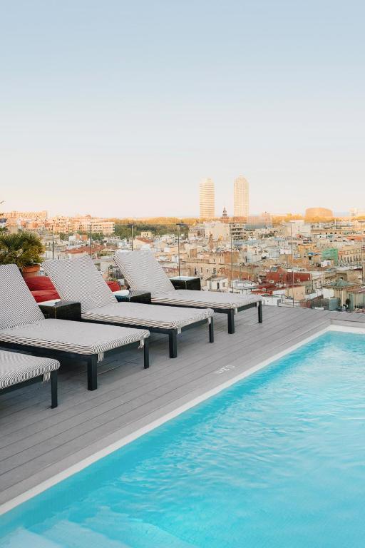 a row of chaise lounges sitting on a deck by a pool at Uma House by Yurbban Trafalgar in Barcelona
