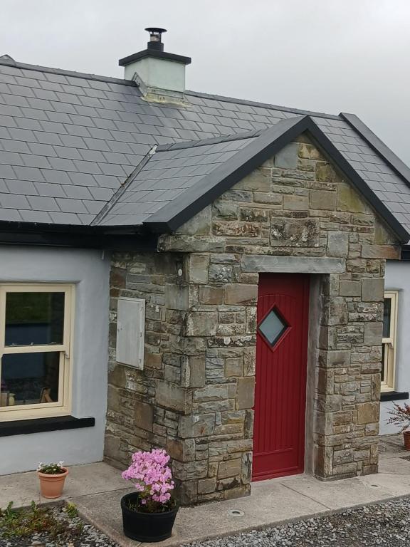 a stone building with a red door at Liam's Cottage Bed and Breakfast in Lisdoonvarna
