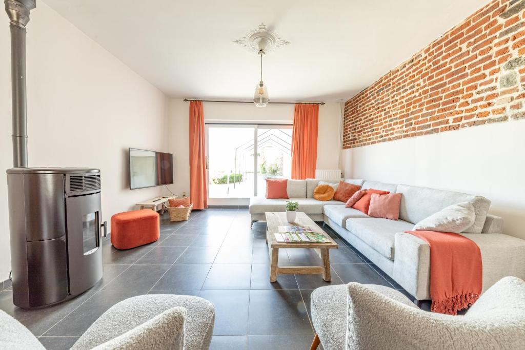 a living room with a couch and a brick wall at Gîte Athois la campagne in Ath