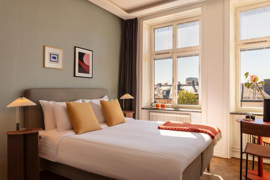 a bedroom with a bed and two windows at Bob W Stockholm Södermalm in Stockholm