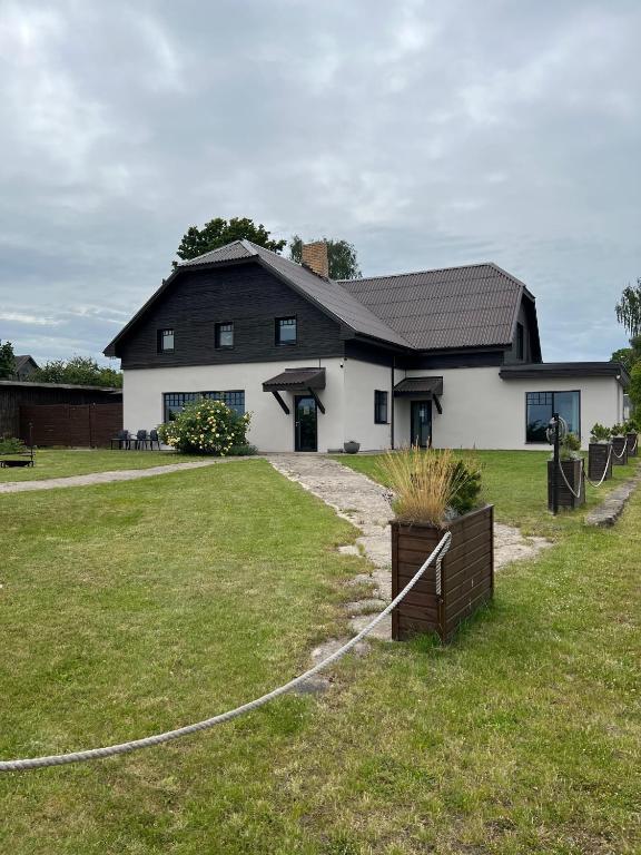 a black and white house with a yard at Mazā Kaija in Bērzciems