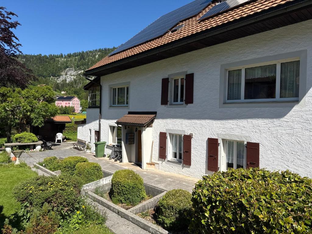 a white house with brown shutters and a yard at Pâquier 3 in Saint-Sulpice
