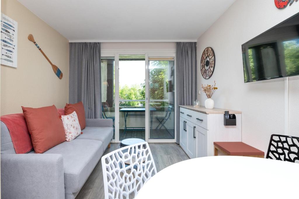 a living room with a couch and a kitchen at Appartement 4p - piscine partagée in Arzon