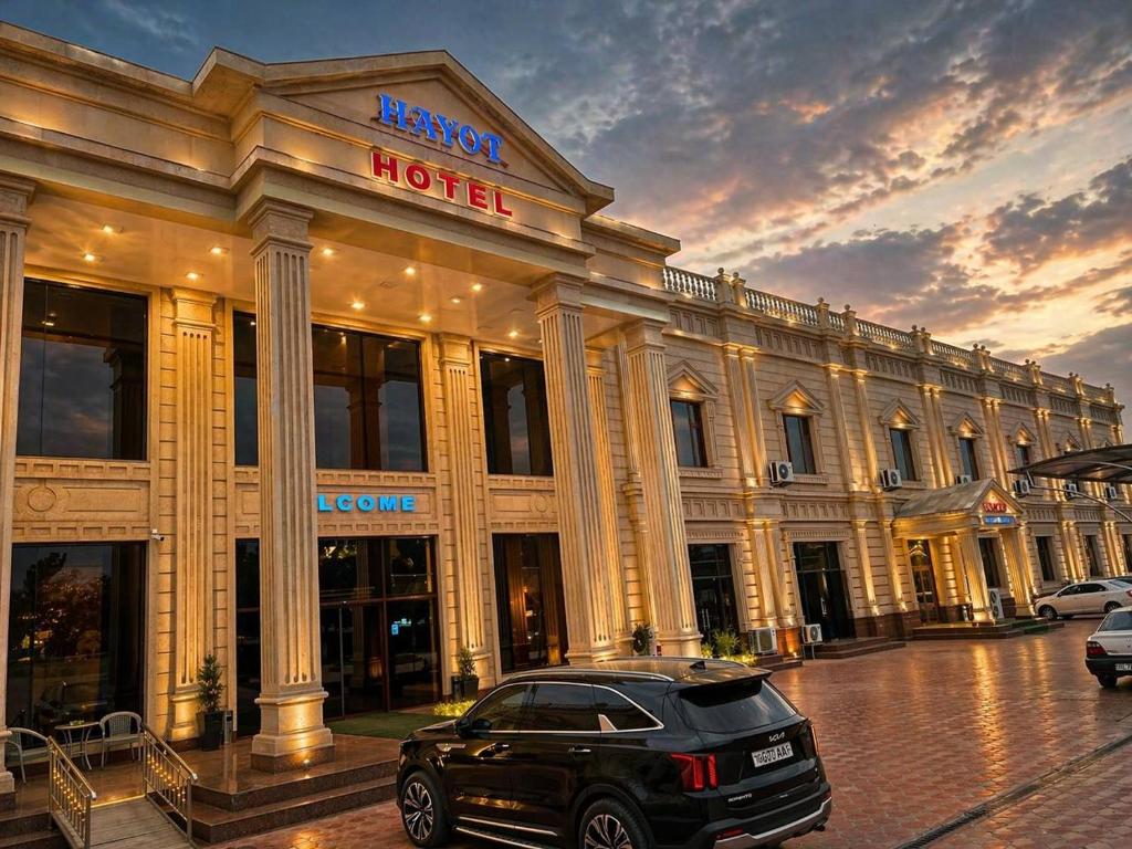 a black car parked in front of a hotel at Hayot Hotel Skazka in Qarshi