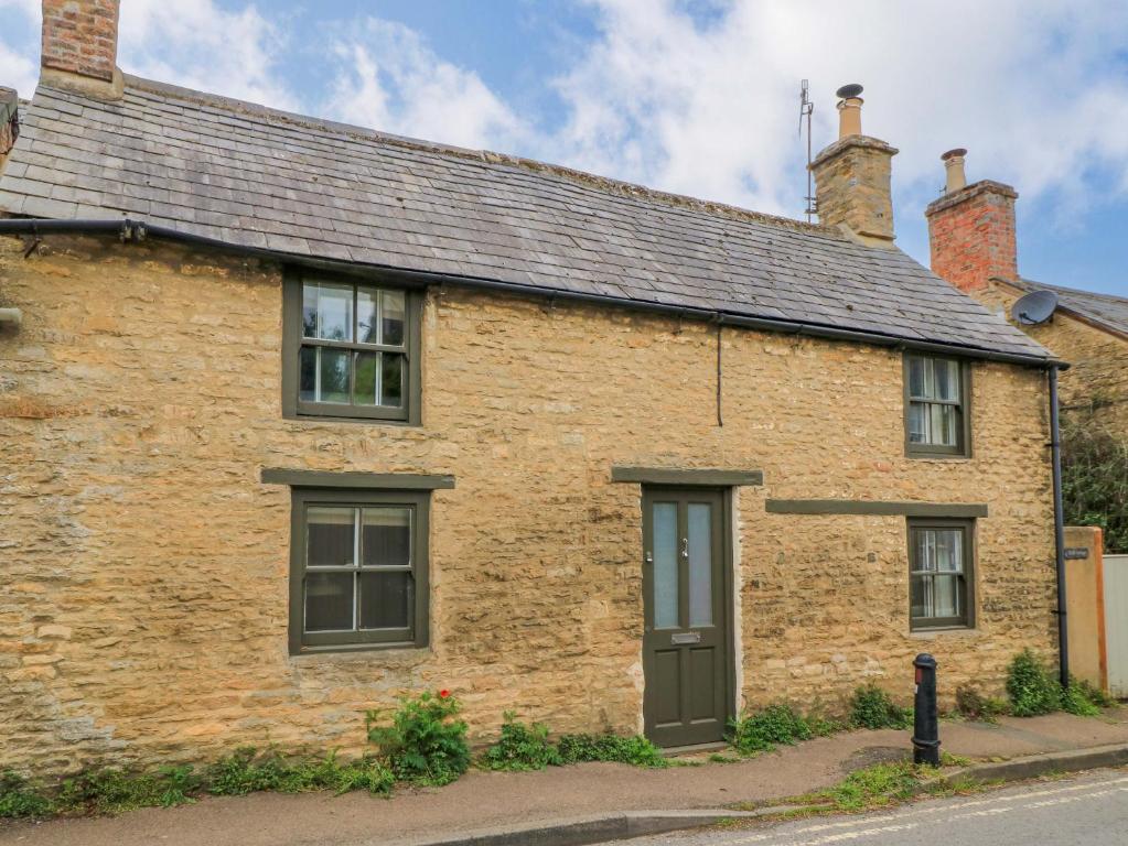 an old brick house on the side of the road at Well Cottage in Chipping Norton