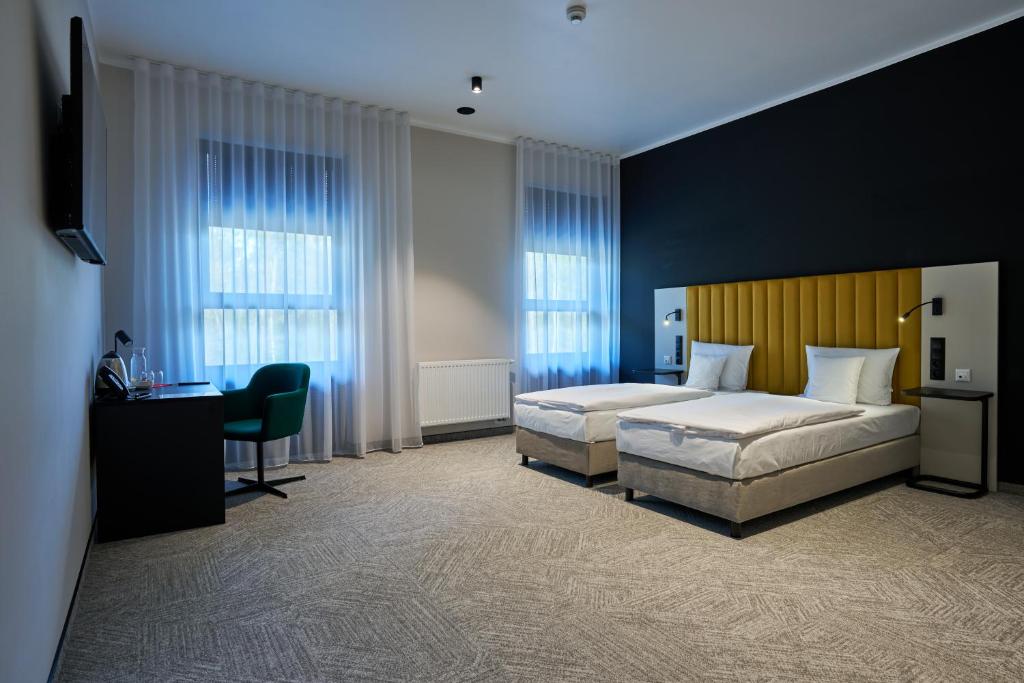 a hotel room with two beds and a desk and window at Hotel Nowa Bukowa in Katowice
