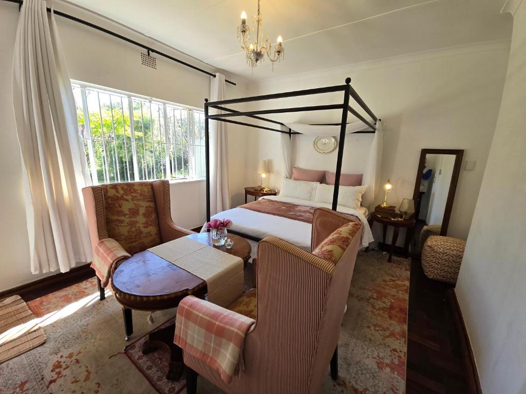 a bedroom with a bed and a table and chairs at Amourette's Rose Cottage in Centurion
