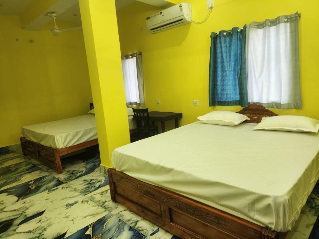 two beds in a room with yellow walls at Hotel Navin Palace Pirpainti in Bhāgalpur