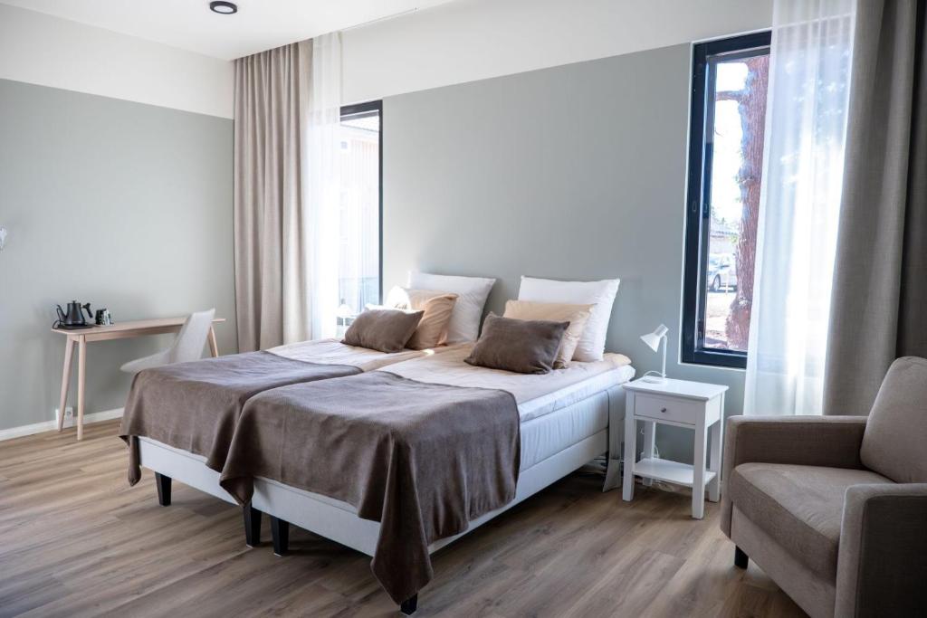 a white bedroom with a bed and a chair at Ruustinna Hotelli & B&B Majoitus in Saarijärvi