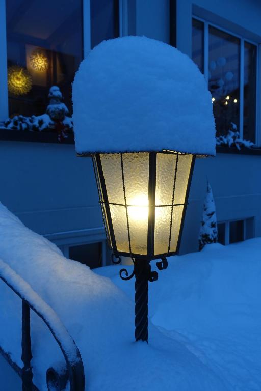 a street light covered in snow in front of a house at Hotel Schweizerhof in Engelberg