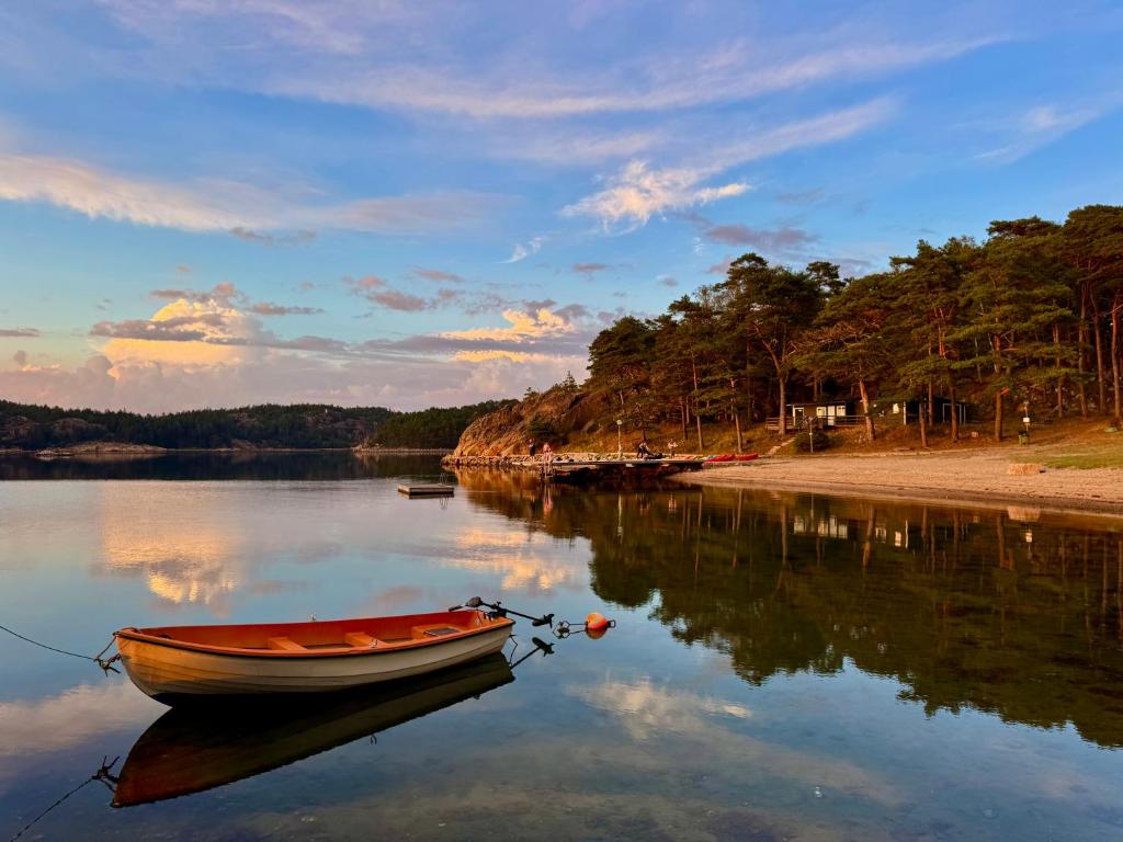 a boat sitting in the water on a lake at Hällestrand Vandrarhem - Lägenhet "Laxen" in Strömstad