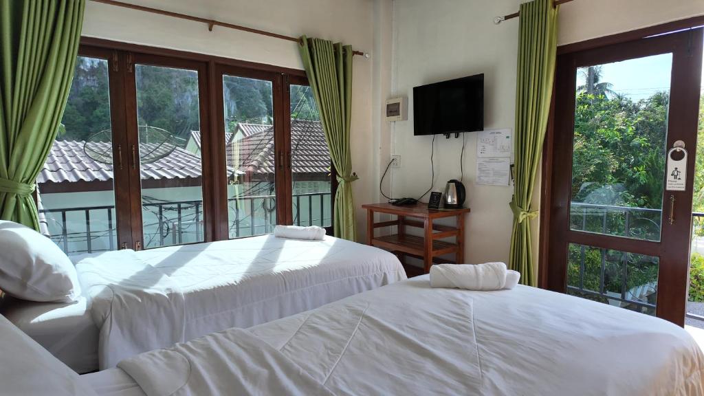 two beds in a room with a window at Sanfhan Resort-SHA Plus in Khao Chai Son