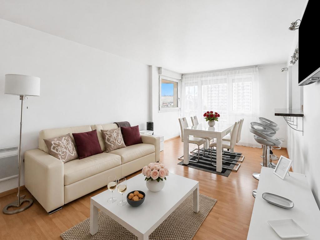 a living room with a couch and a table at Porte de Paris, spacieux T3, terrasse et parking in Vanves