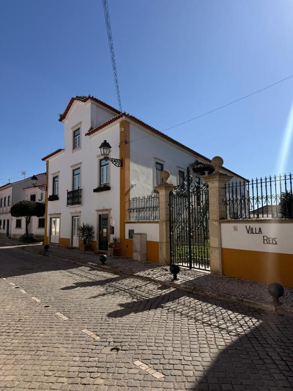 a white and yellow building with a gate on a street at Villa Reis - Boutique House in Golegã