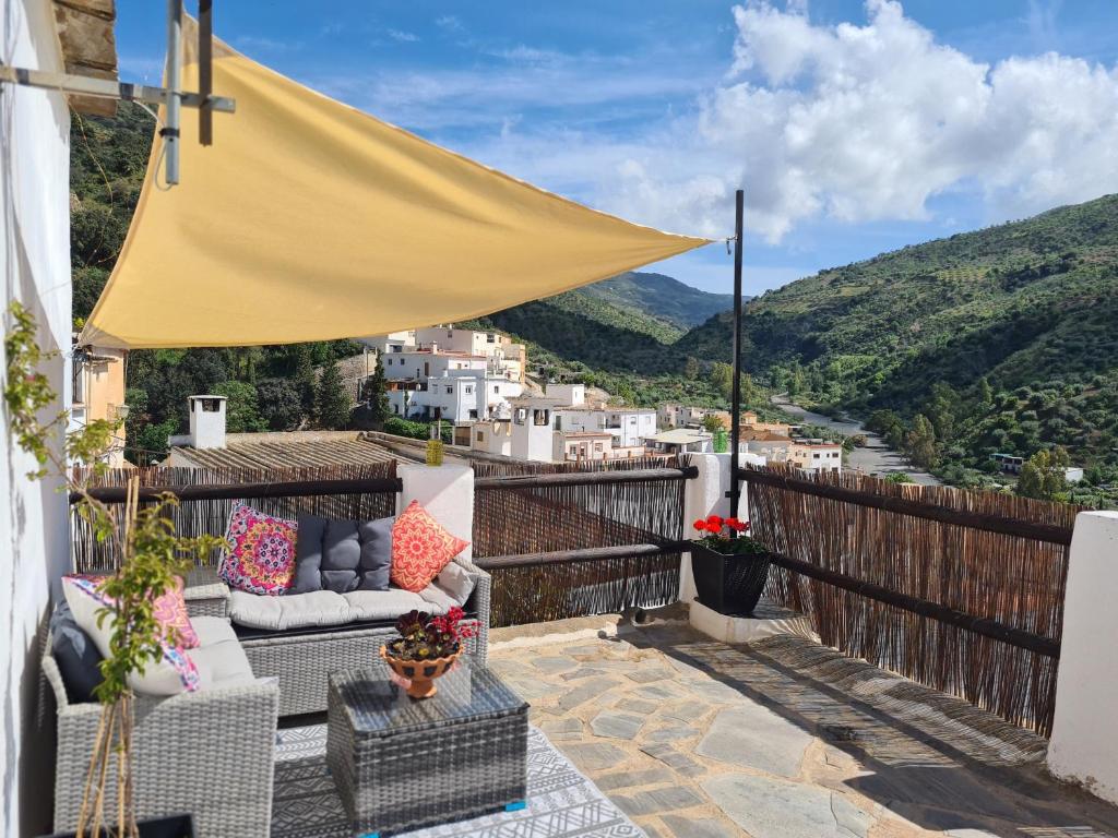a balcony with chairs and a yellow umbrella at El Pequeño Escondite in Torviscón
