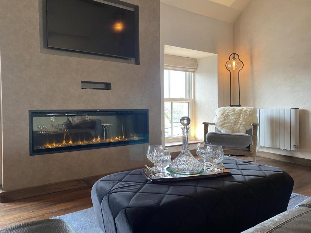 a living room with a fireplace and a table with wine glasses at The Loft at Design Bank in Milltown Malbay