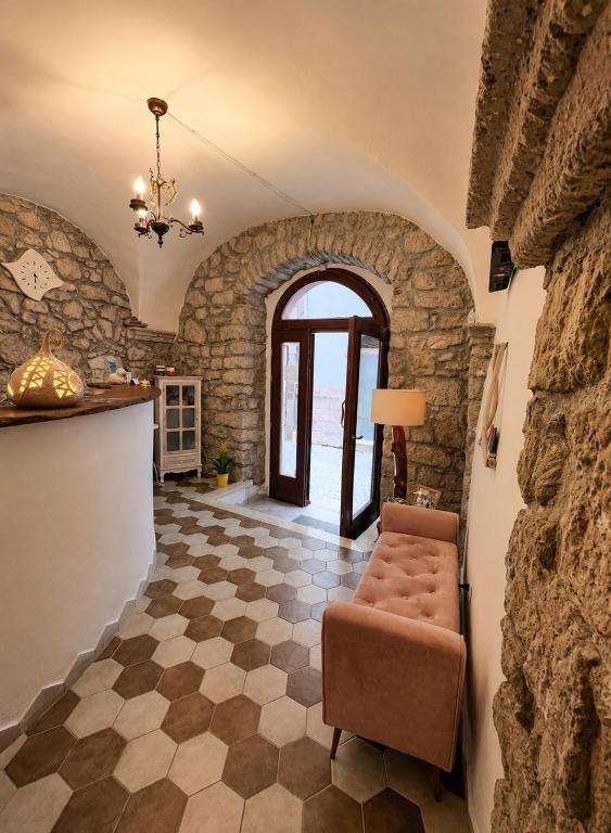 a living room with a chair and a stone wall at Regnos Altos boutique rooms in Bosa