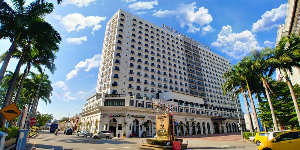 a large building on a city street with palm trees at Imperial Heritage Hotel Melaka I City Centre I Free Wifi I Free Parking l Free Club Lounge Access in Malacca