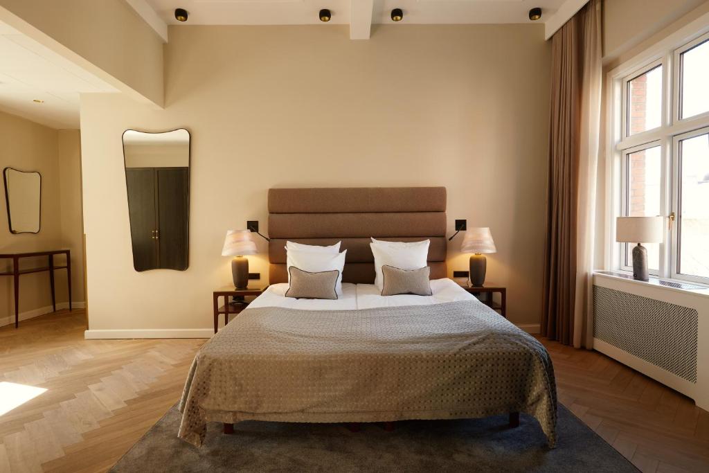 a bedroom with a bed with two lamps and a mirror at Ascot Hotel in Copenhagen