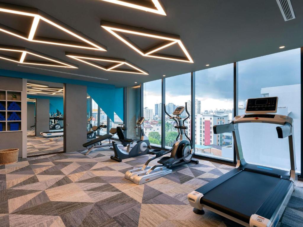 A bright, window-lined gym with cardio machines and city-facing windows.