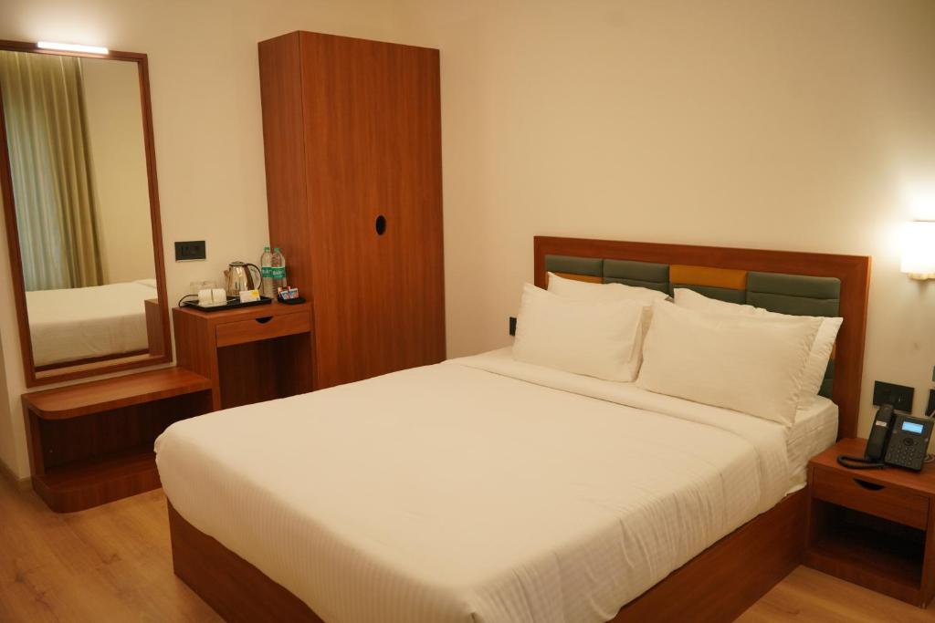 a bedroom with a large bed and a mirror at Hotel Grand Vekasa in Salem