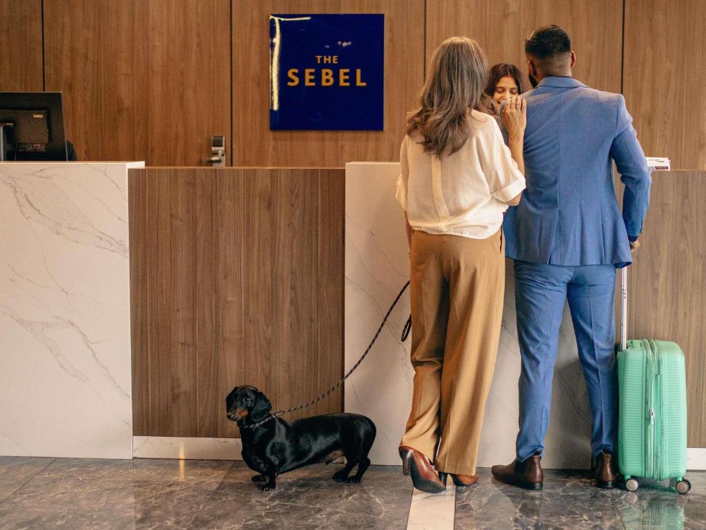 a man and a woman with a dog on a leash at The Sebel Canberra Civic in Canberra