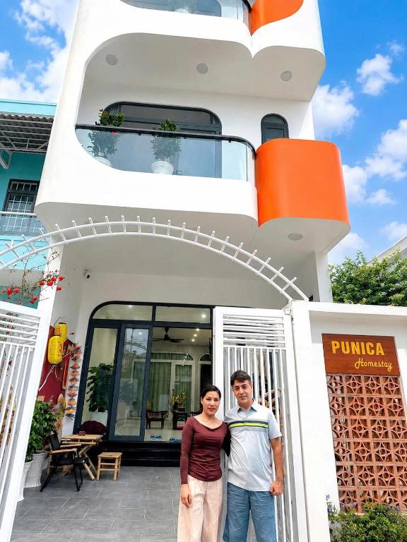 a man and a woman standing in front of a house at Punica Homestay in Tuy Hoa