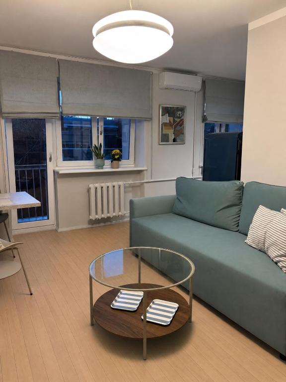 a living room with a green couch and a glass table at Jurmala Cozy Vibes - self check in in Jūrmala