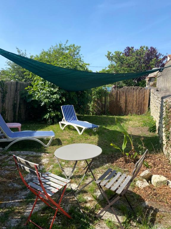 a table and chairs in a yard with a tent at Oléron Central in Saint-Pierre-dʼOléron