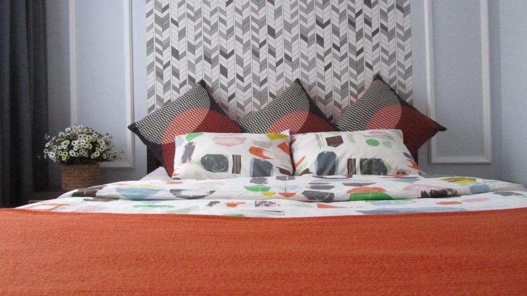 a bed with an orange blanket and pillows on it at City Charm Warszawa in Warsaw