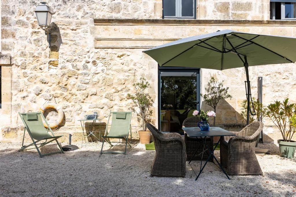a table with chairs and an umbrella in front of a building at Studio Bord-Eau, terrasse et jardin in Saint-André-de-Cubzac