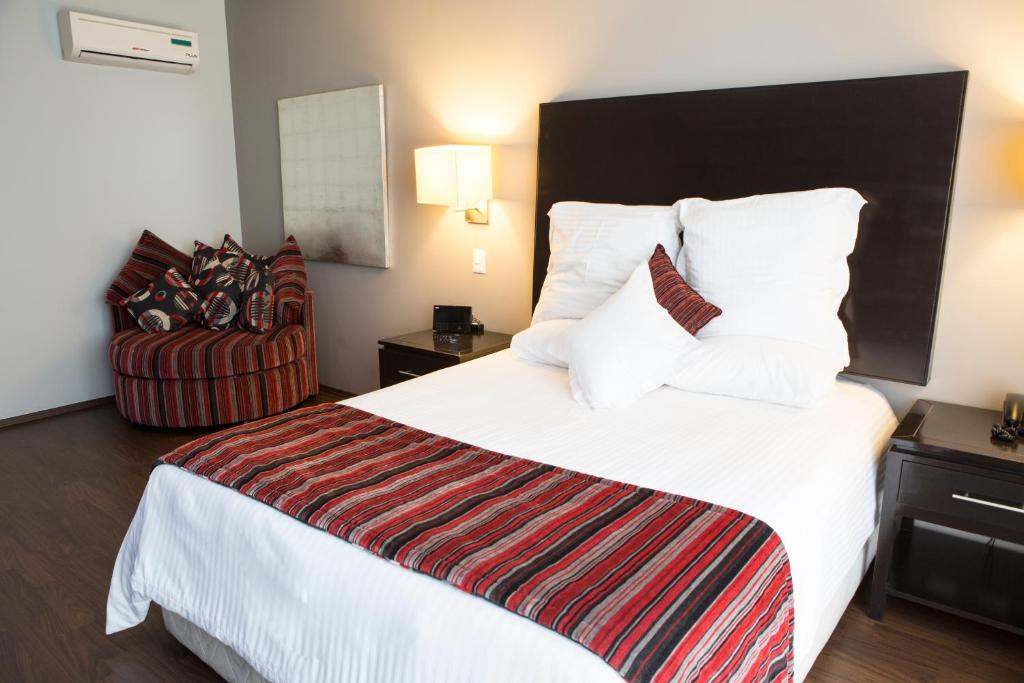 una habitación de hotel con una cama grande y una silla en Suites Ganges, en Ciudad de México