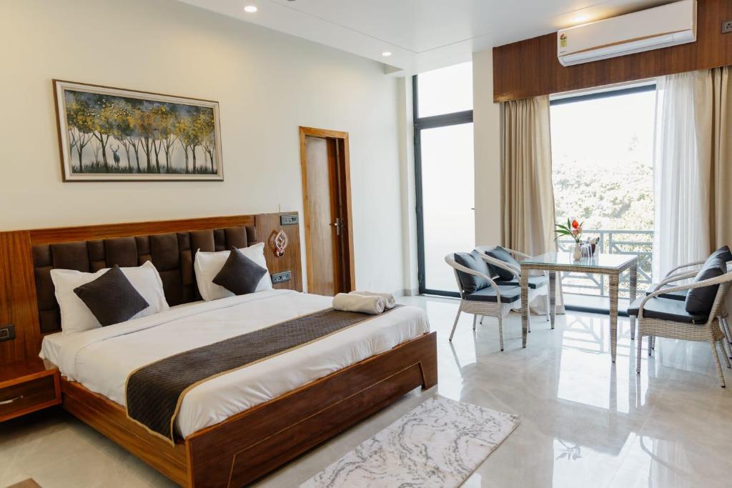 a bedroom with a bed and a table and chairs at The Twelve Petals by Parvati Inn in Dhikuli