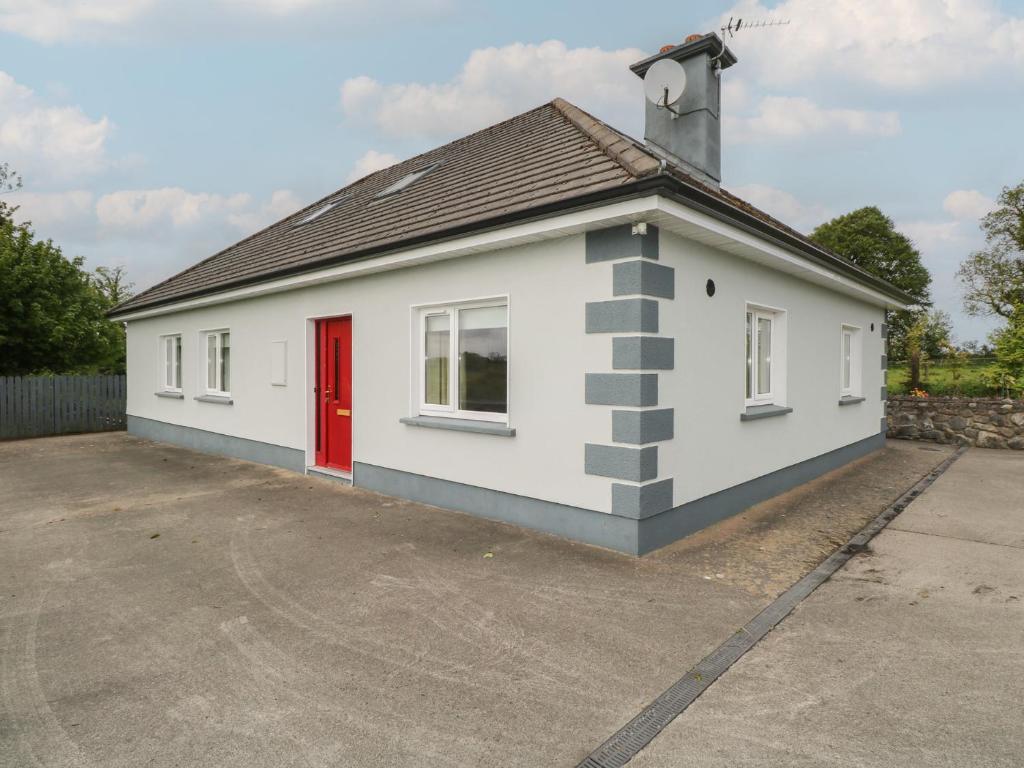 a small white building with a red door at River House in Ballina