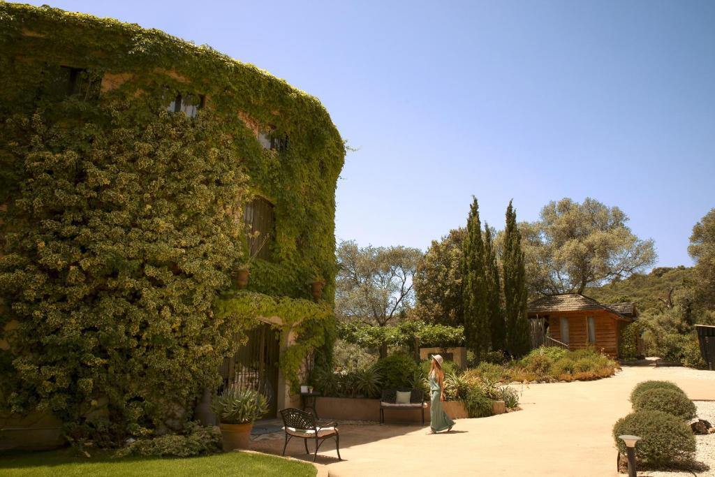 a building covered in green ivy next to a garden at L'Hostellerie du Moulin des Oliviers in Olmeto