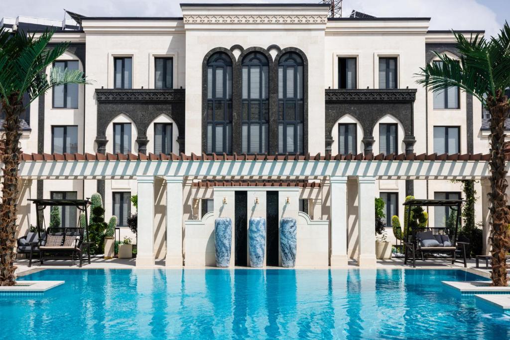 a hotel with a swimming pool in front of a building at Mustafa Hotel in Samarkand
