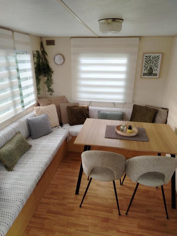 a living room with a couch and a table and chairs at Le Bruant des Roseaux in Villegusien Le Lac