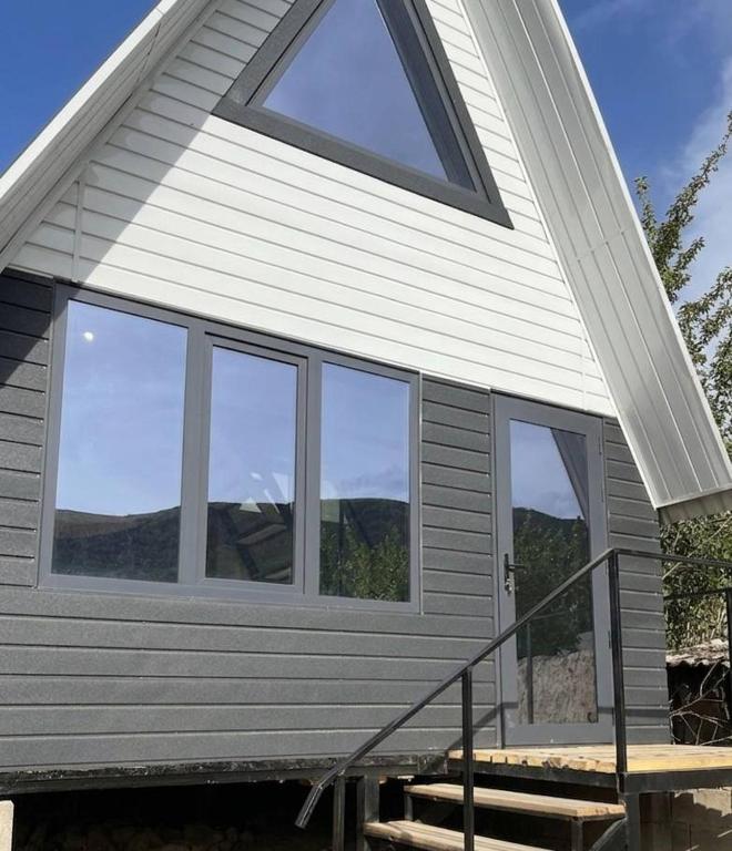 a house with windows on the side of it at A frame house with a view of mountains in Karakol