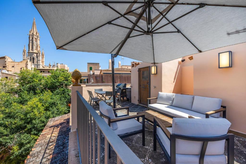 a balcony with a couch and chairs and an umbrella at Casa del Call in Palma de Mallorca