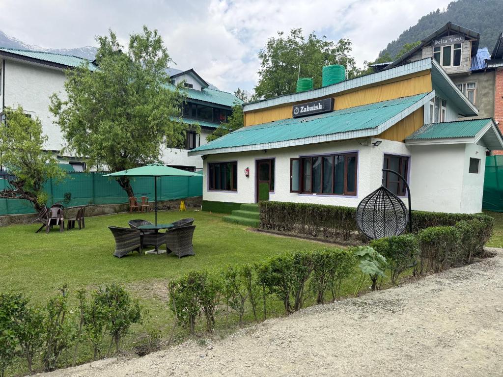 a house with a yard with two chairs and a table at Zabaish Riverside Cottage in Pahalgām