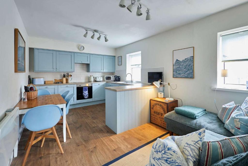a kitchen and living room with blue cabinets at The Bamburgh Bolthole in Bamburgh