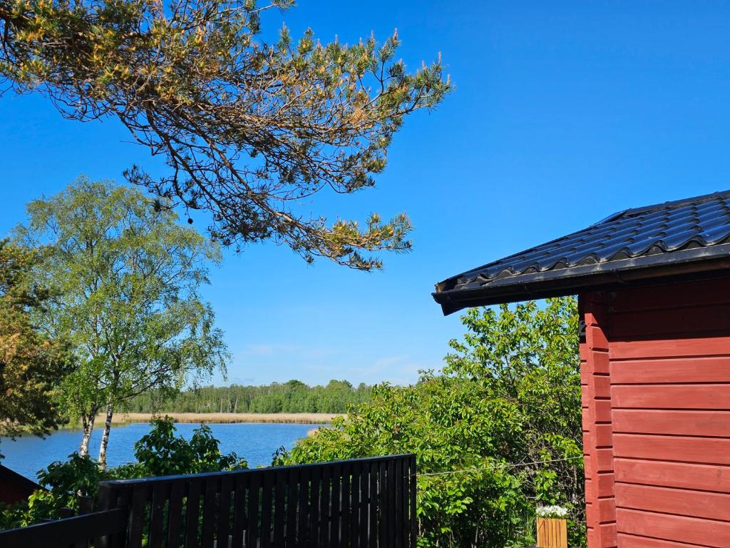 a red house with a view of a lake at Stuga 21 i Dalskärs Camping in Bergkvara