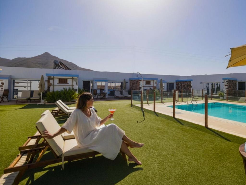 a woman sitting on a chair next to a pool at Hotel Boutique Rosario Martin in Puerto del Rosario