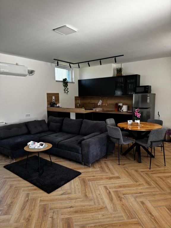 a living room with a couch and tables and a kitchen at Dominó Apartman in Gelse