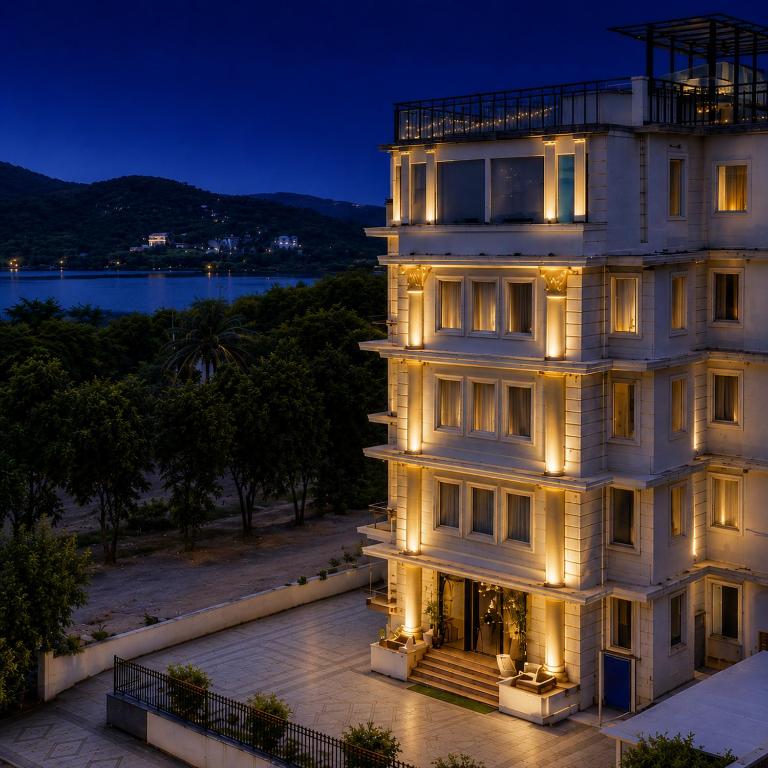 a building with its lights on at night at The Colonial - A Lake View Hotel in Udaipur in Udaipur