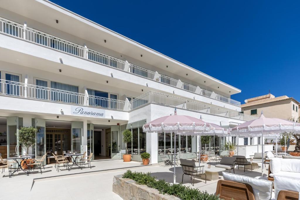 an exterior view of a hotel with tables and chairs at Hoposa Panorama in Port de Pollensa